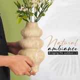 Person holding a 9 inches natural travertine marble flower vase filled with artificial flowers – perfect for living room, dining table, or home decor accent piece, highlighting earthy texture and outdoor-inspired ambiance.