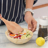 Large travertine bowl used as salad serving bowl with lettuce, tomatoes, and cucumbers, onions.