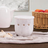 white marble travertine garlic and onion holder placed with fresh vegetables on kitchen counter