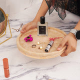 Round travertine tray organizing perfumes and makeup in bathroom