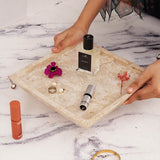 Square travertine tray organizing perfumes and makeup in bathroom