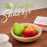 Top view of travertine fruit bowl filled with apples and grapes, placed on wooden table.