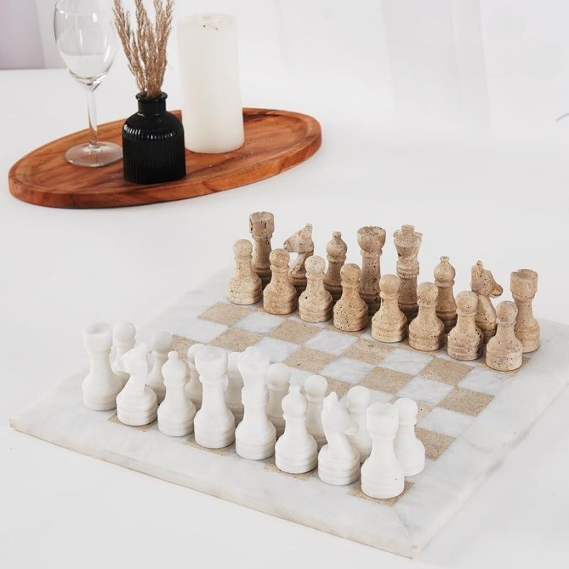 Top view of white and travertine marble chess board during play