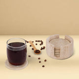 Travertine marble coaster set with holder displayed on a beige table with a glass of coffee, coffee beans, and a wooden spoon – natural stone drink coasters for kitchen or home use.