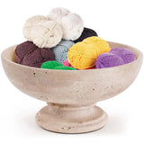 Travertine marble fruit dish used as a yarn holder with colorful yarn balls with white background