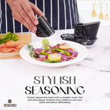 Hand sprinkling salt on fresh salad using marble salt and pepper shakers with tray in black