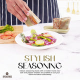 Hand sprinkling salt on fresh salad using marble salt and pepper shakers with tray in green