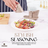 Hand sprinkling salt on fresh salad using marble salt and pepper shakers with tray in oceanic