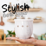 white marble garlic holder with garlic bulbs on countertop