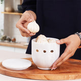Garlic stored in open white marble garlic container with lid off