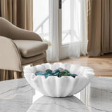 White ruffle marble bowl with scalloped edges used as a decorative centerpiece on a marble table