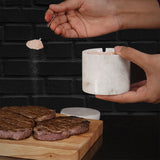 white marble salt cellar used for seasoning on kitchen countertop